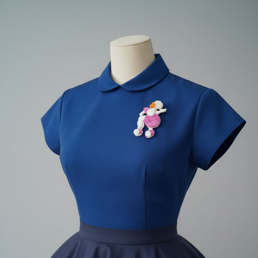 Pink and white poodle-shaped brooch pinned on a blue bouse