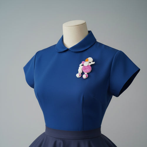 Pink and white poodle-shaped brooch pinned on a blue bouse