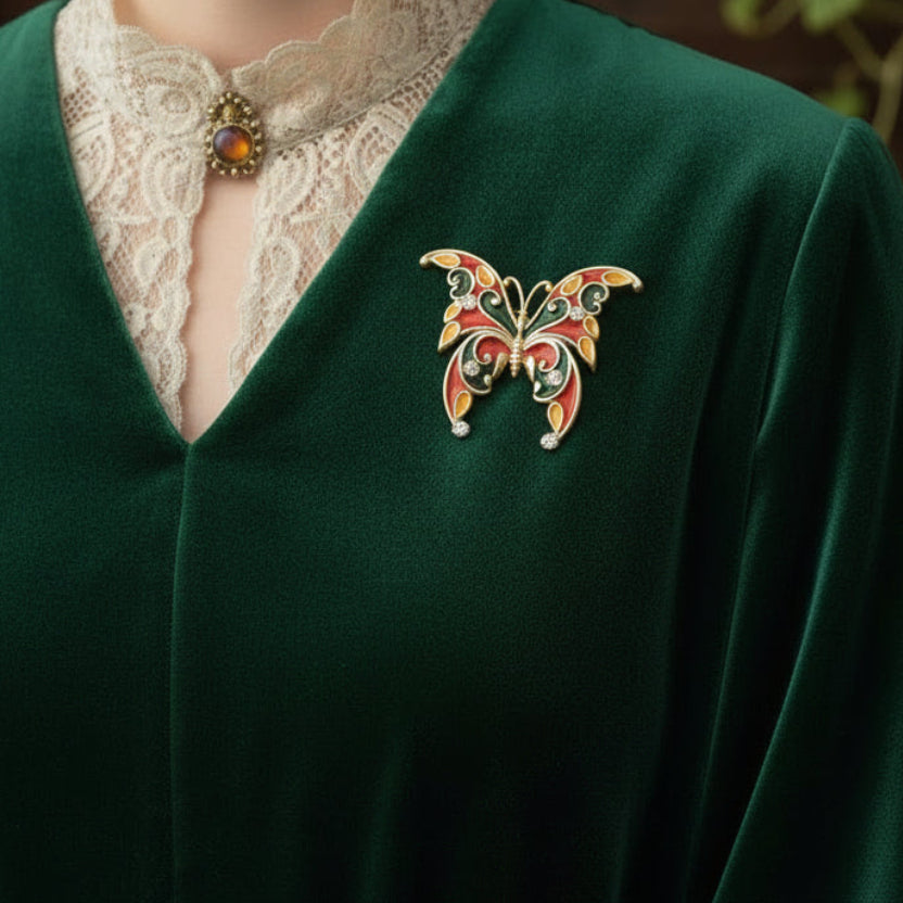 Butterfly-shaped brooch with red, green, and gold colors on a green dress