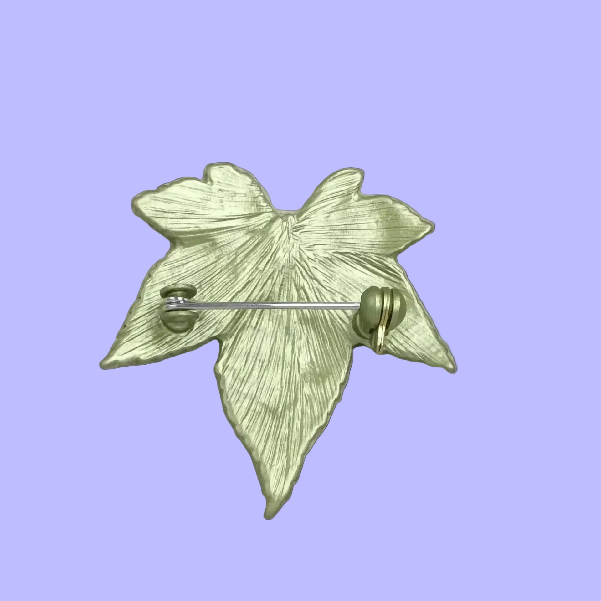 Back view of green leaf-shaped brooch showing the clasp mechanism 