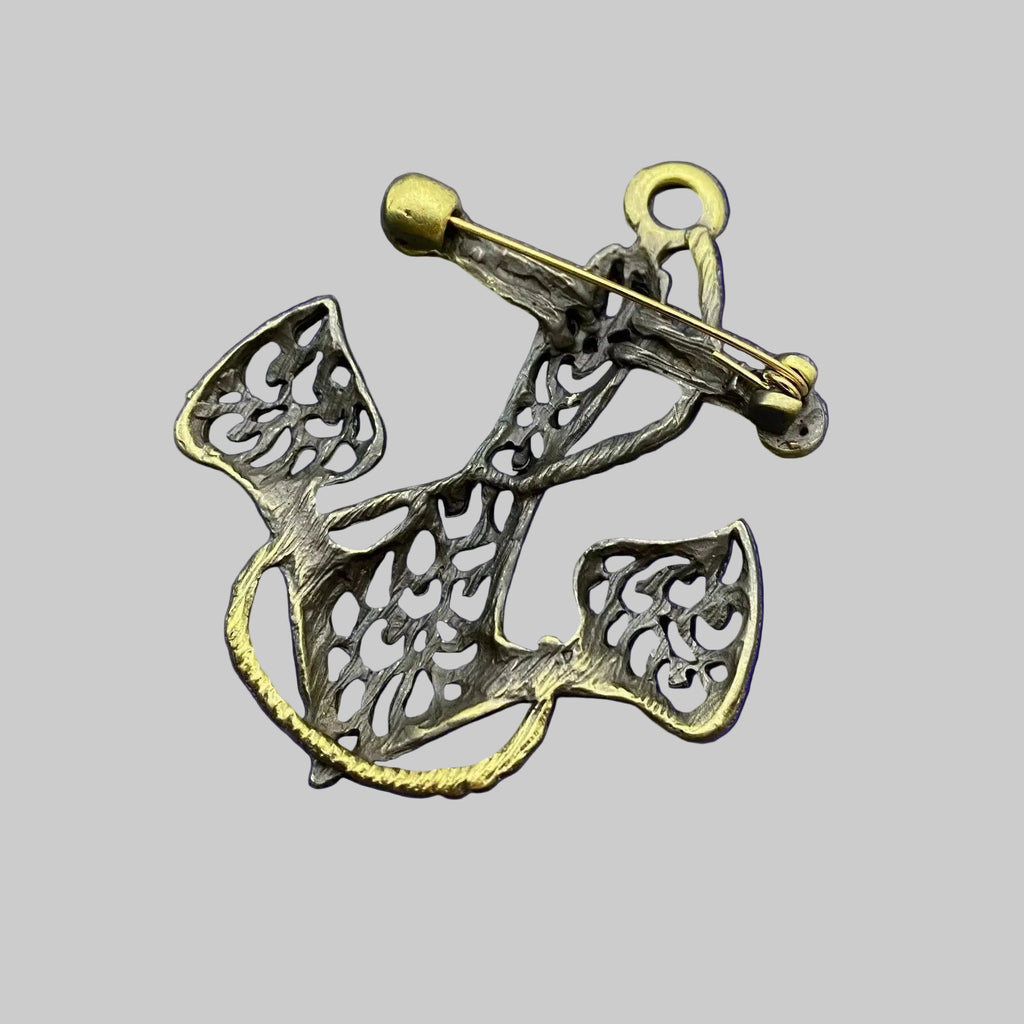 Back view of bronze anchor-shaped brooch showing the clasp mechanism, against a gray background.