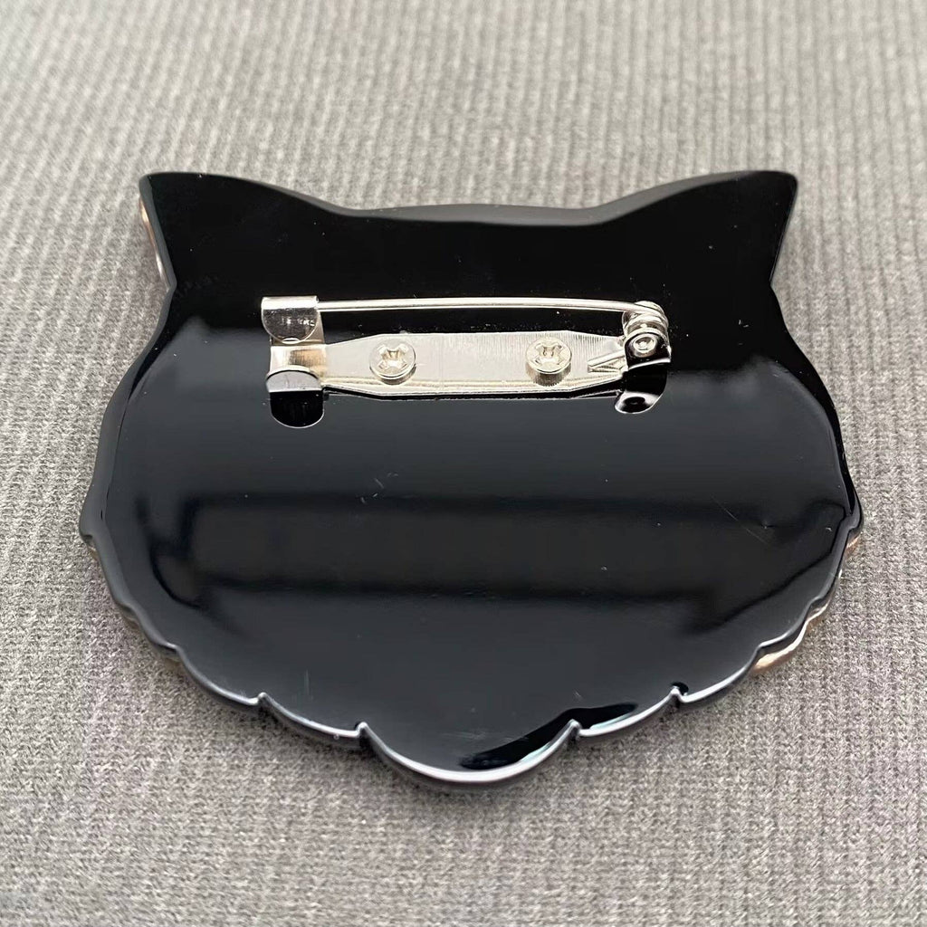 Back view of acrylic cat-shaped brooch with green eyes, showing clasp mechanism