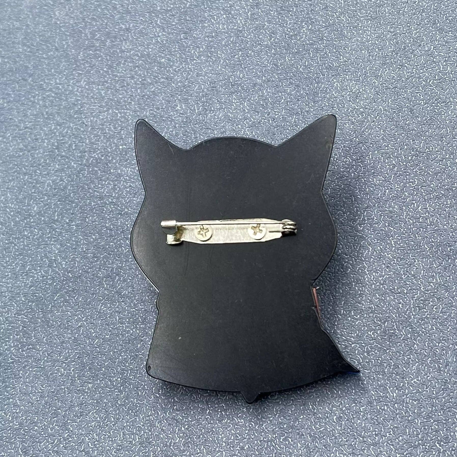 Back view of a cat-shaped brooch with a colorful design showing the clasp mechanism