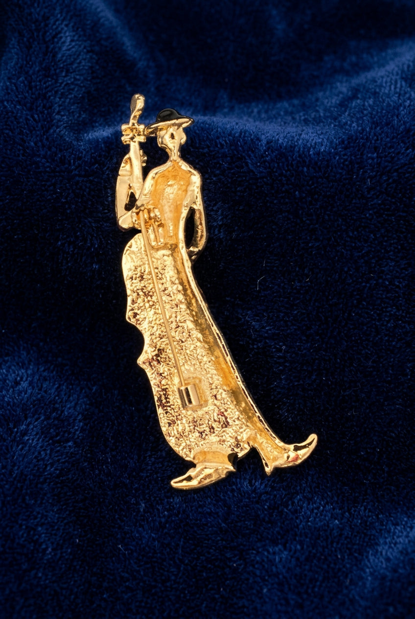 Back view of a cellist brooch featuring the clasp mechanism, against a blue background.