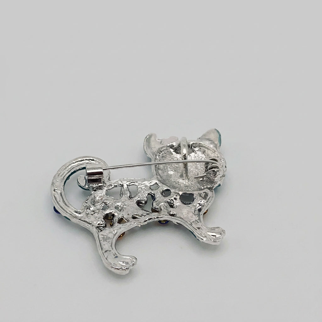 Back view of cat brooch showing the clasp mechanism, against a gray background.