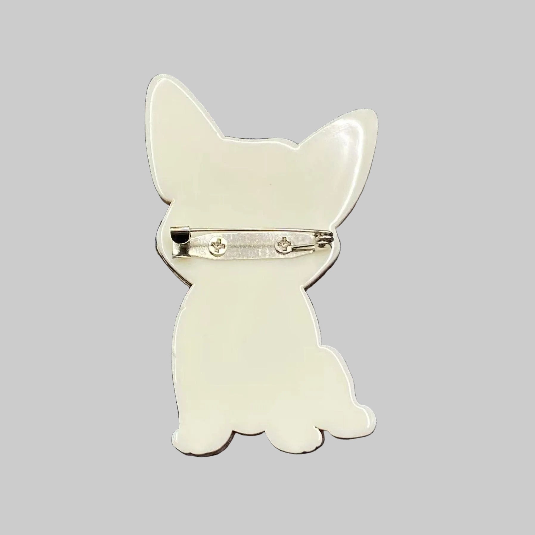 Back view of dog-shaped brooch with a red collar, showing the clasp mechanism
