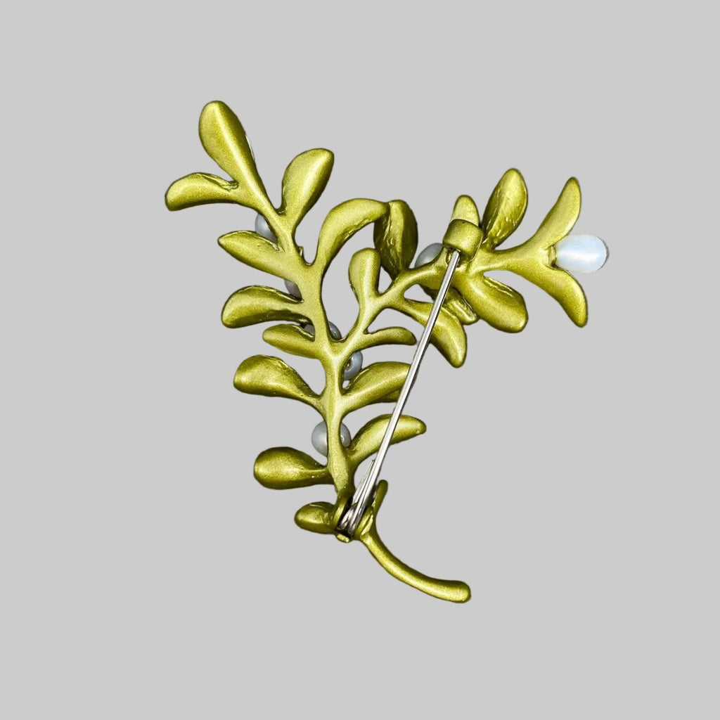 Back view of boxwood plant brooch with green leaves and white berries, showing the clasp mechanism