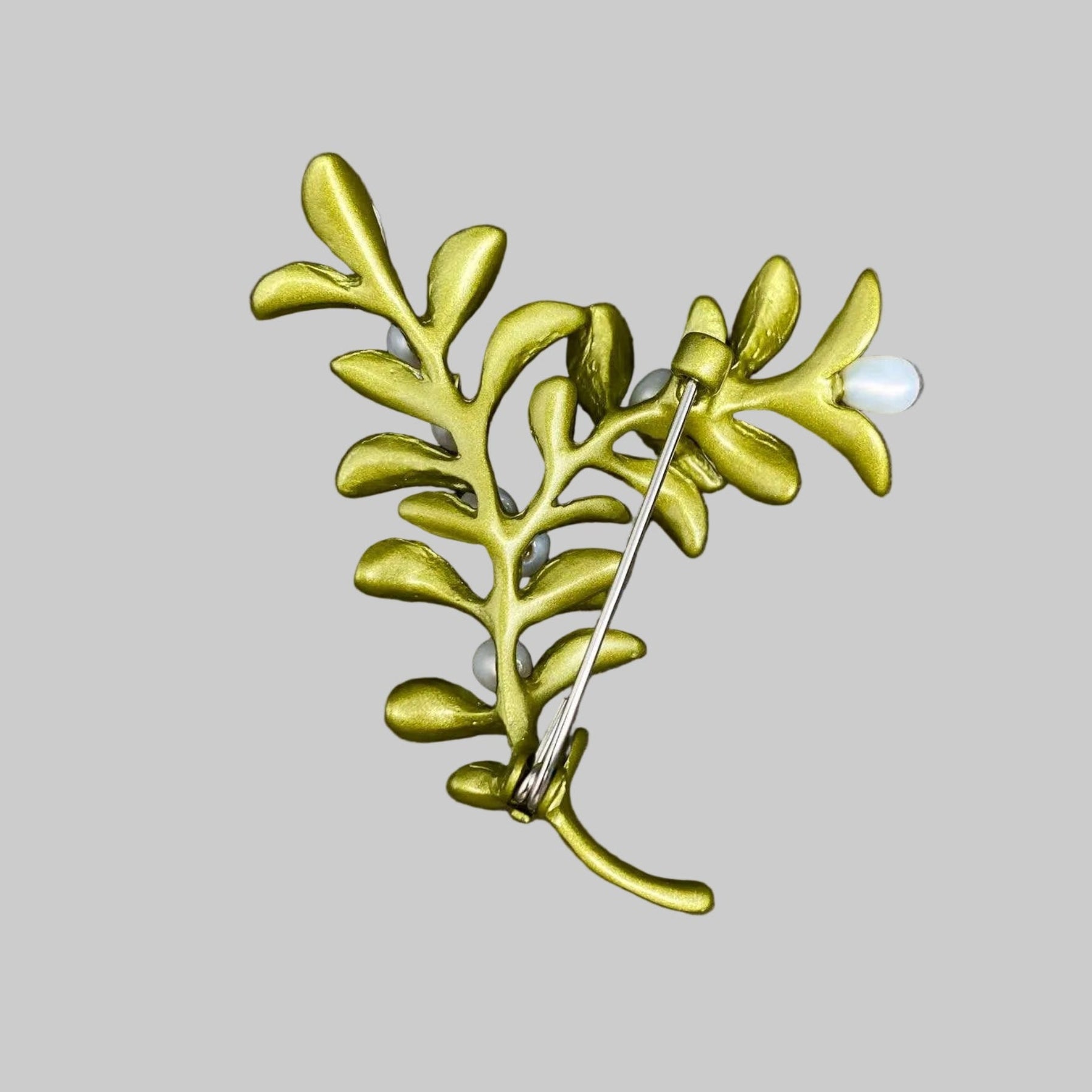 Back view of boxwood plant brooch with green leaves and white berries, showing the clasp mechanism