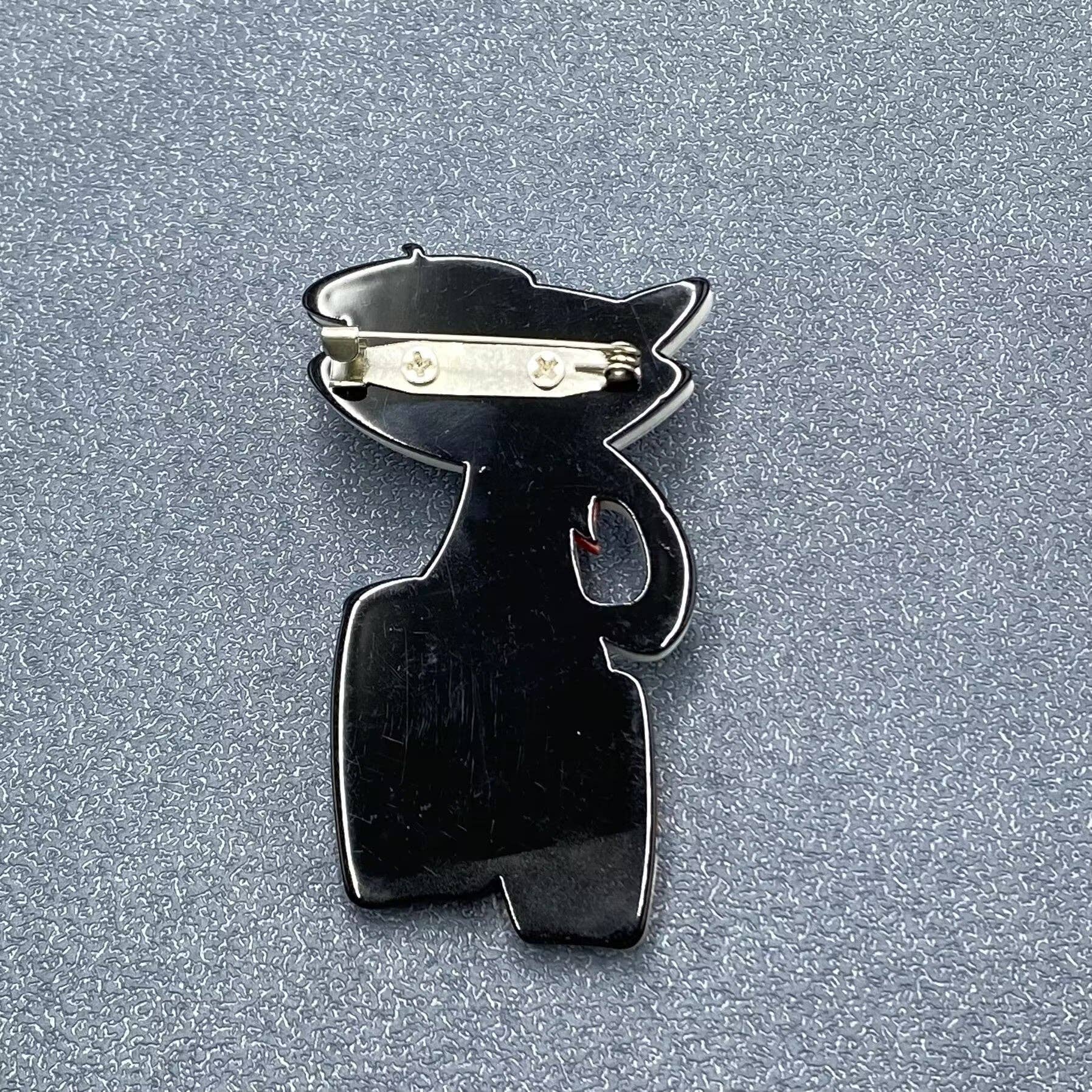 Back view of acrylic cat-shaped brooch with drums showing the clasp mechanism
