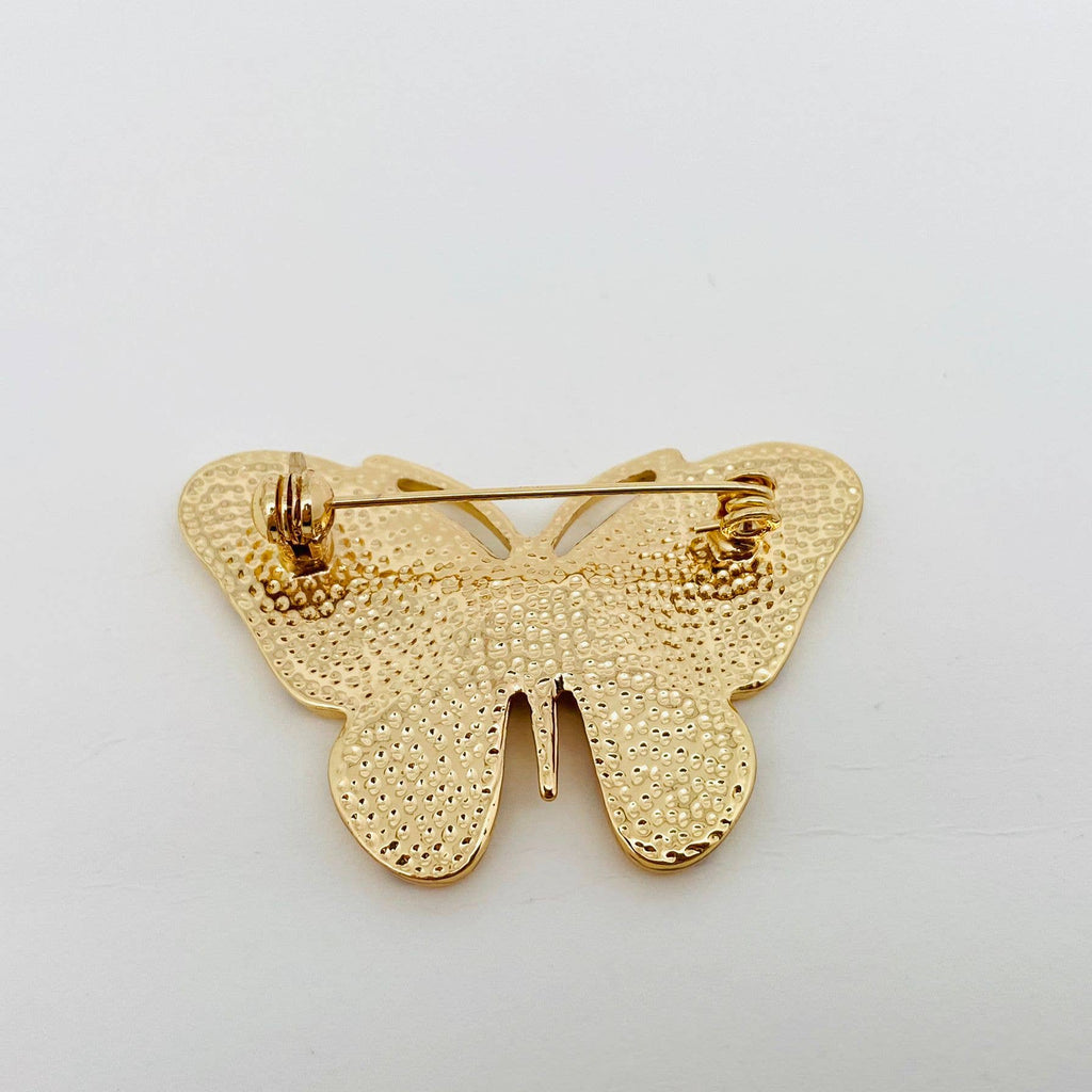 Back view of gold butterfly-shaped brooch with yellow accents, showing clasp mechanism