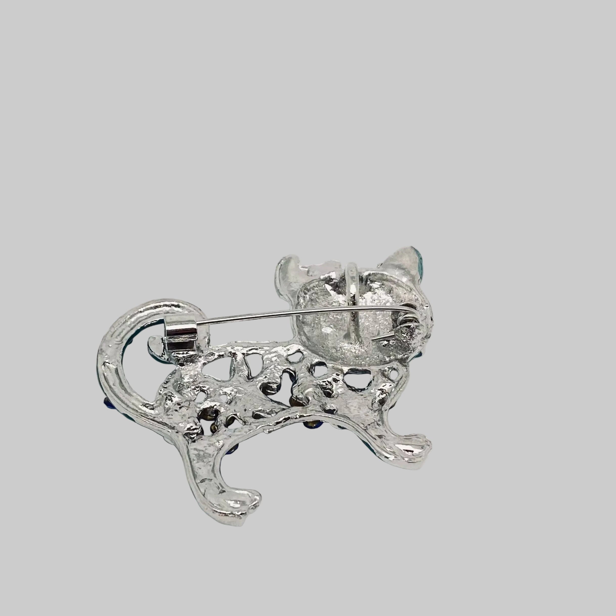 Back view of cat brooch showing the clasp mechanism, against a gray background