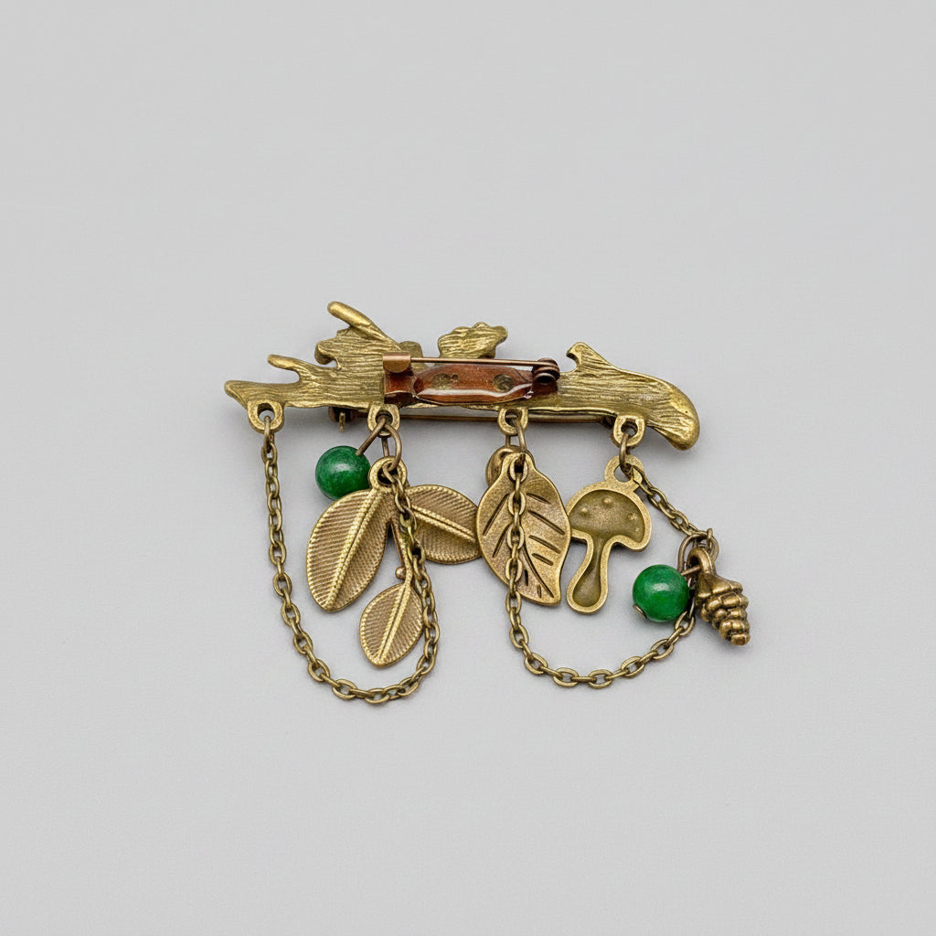 Back view of bronze brooch with nature-themed charms, showing clasp mechanism