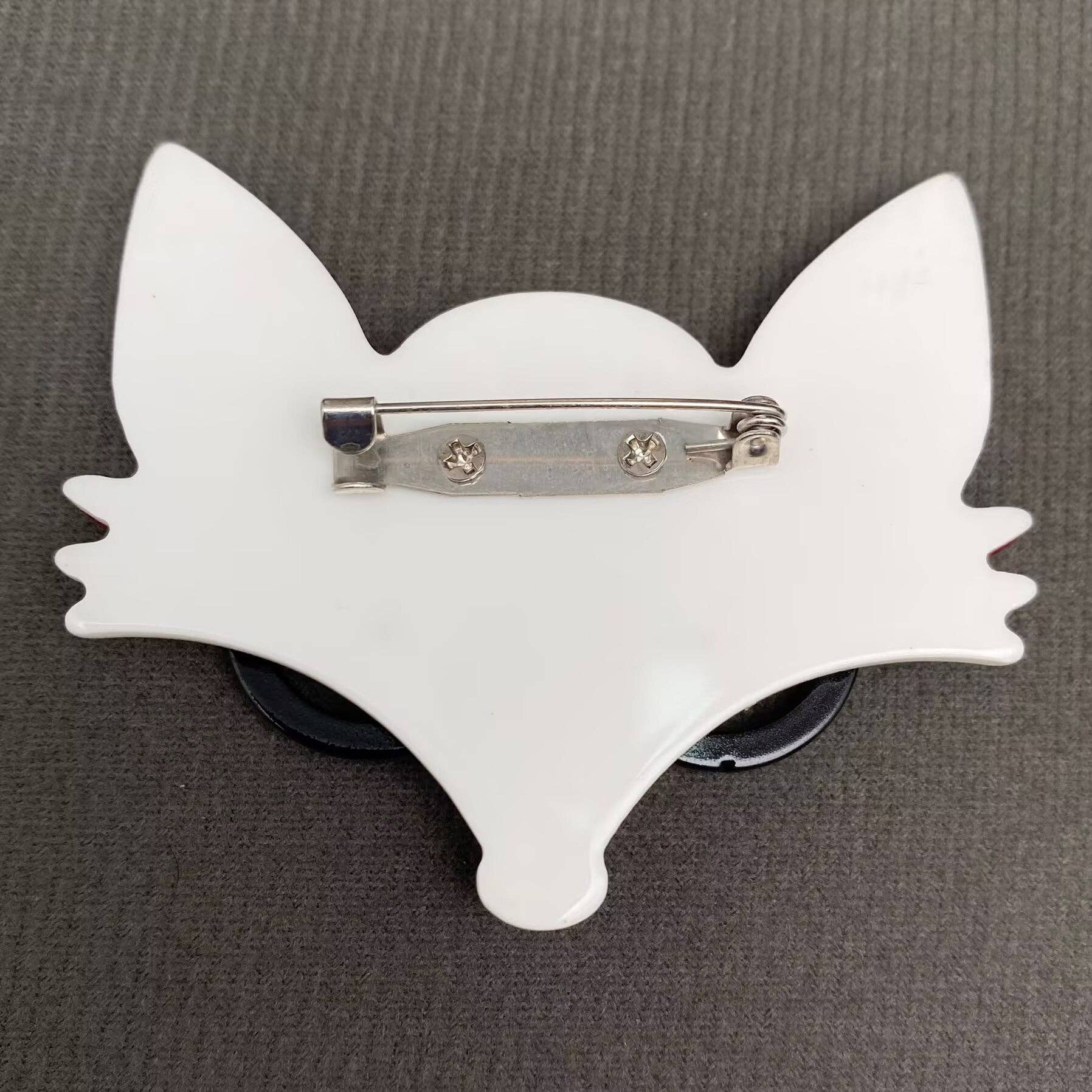 Back view of red fox-shaped brooch with black glasses showing clasp mechanism