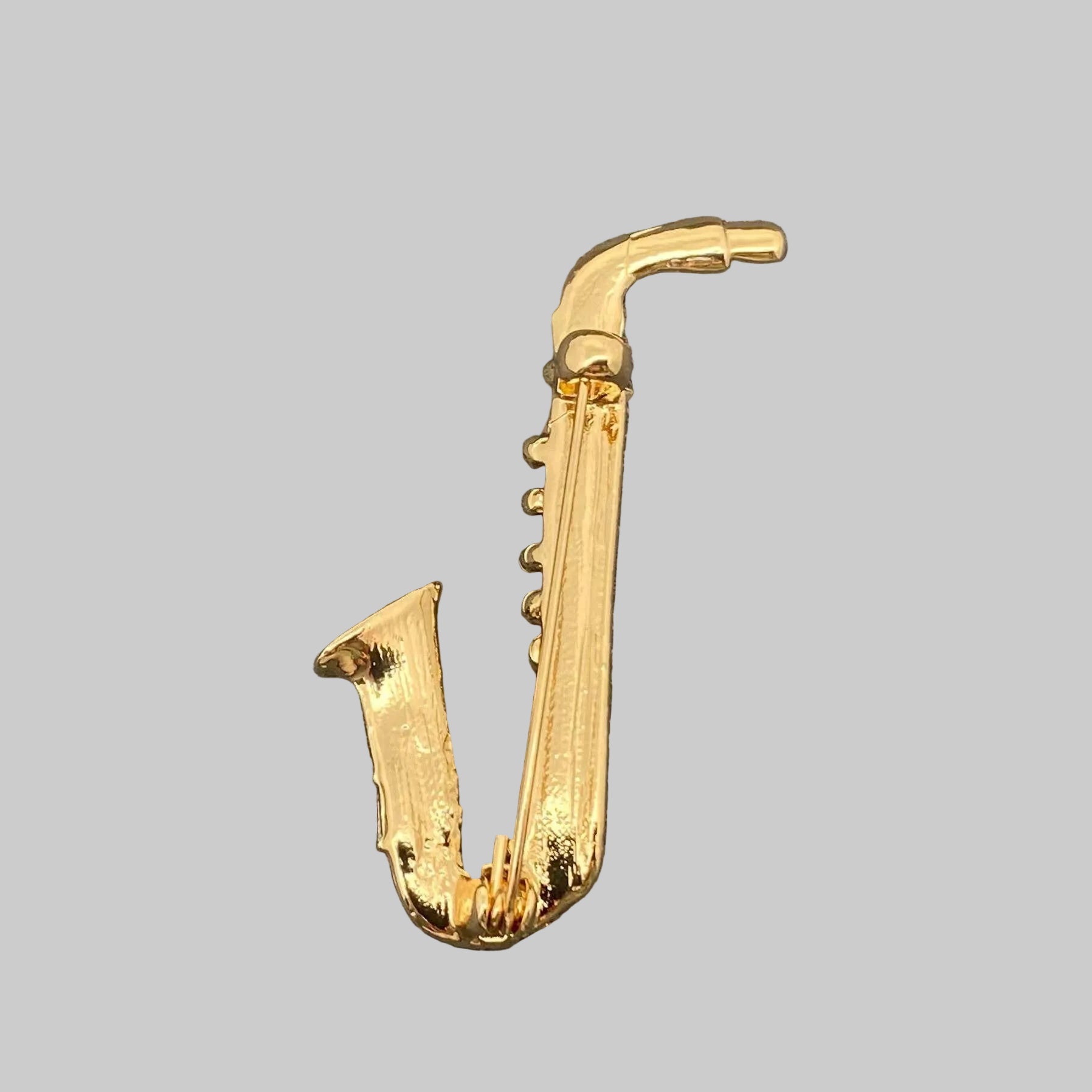Back view of gold saxophone-shaped brooch showing the clasp mechanism