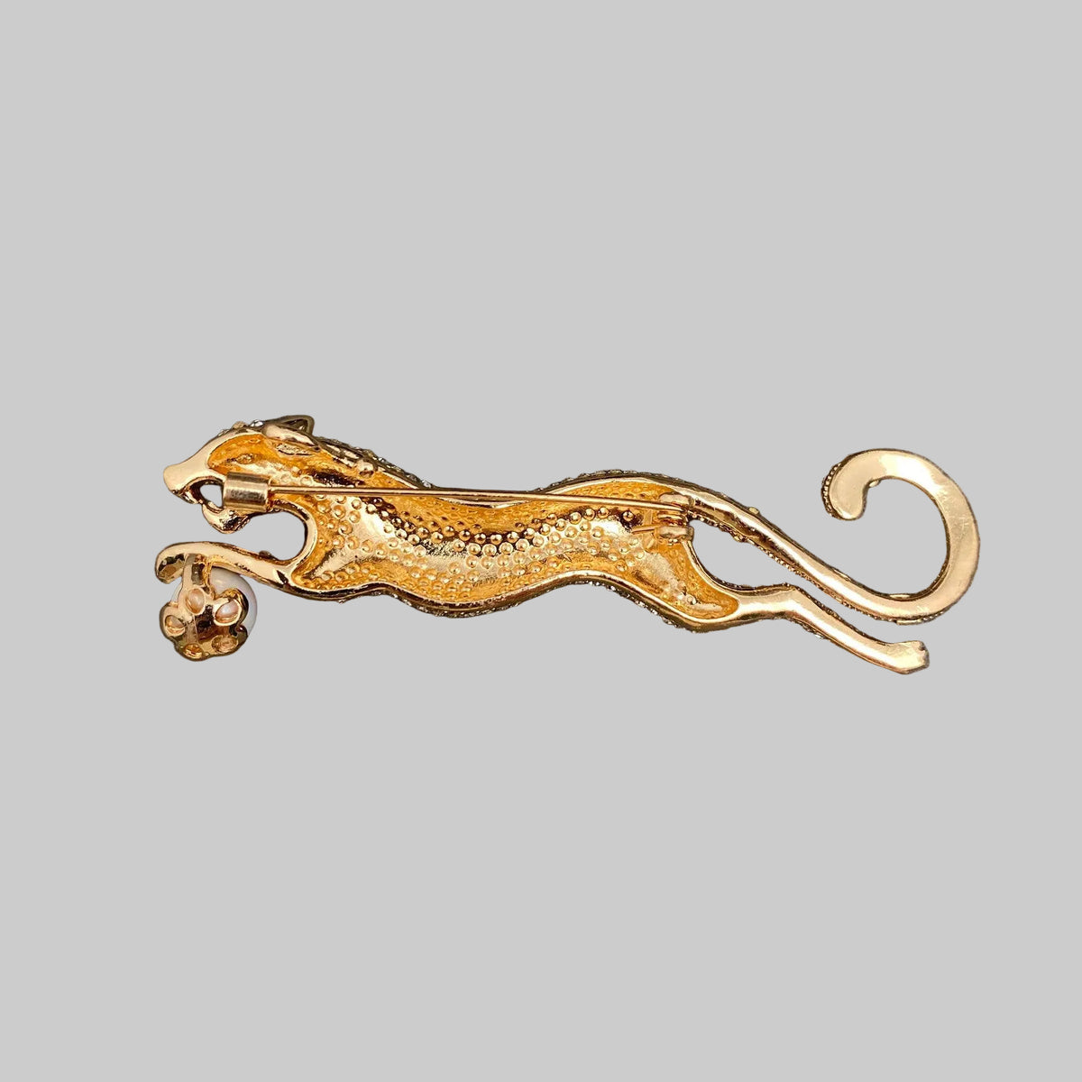 Back view of a cheetah brooch pin showing the clasp mechanism, against a gray background.