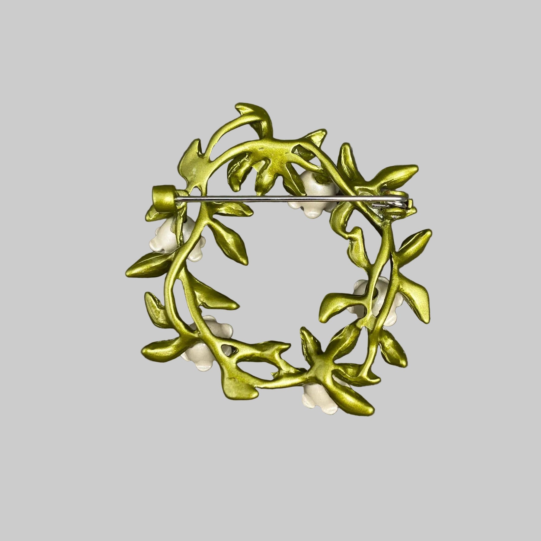 Back view of floral brooch with green leaves and white flowers, showing the clasp mechanism
