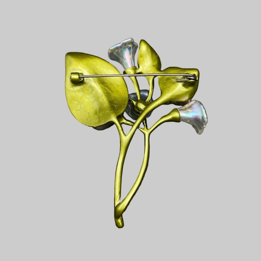 Back view of floral brooch with green leaves and silver flowers, showing the clasp mechanism