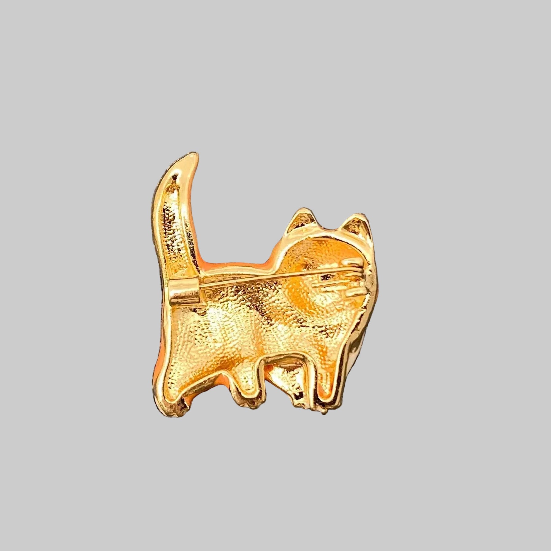 Back view of small orange cat brooch showing the clasp mechanism