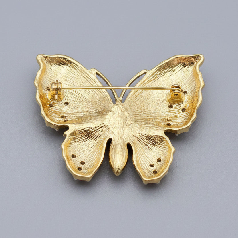 Back view of butterfly-shaped brooch with pink center, showing clasp mechanism