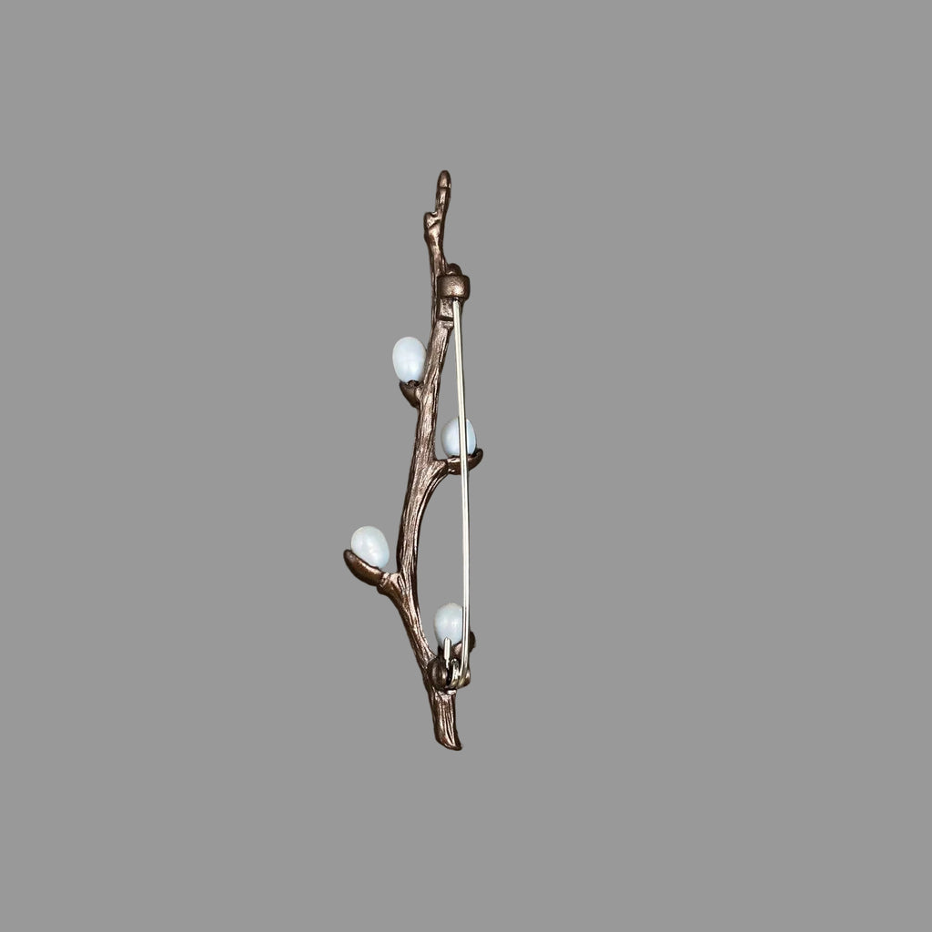 Back view of bronze brooch with branches and small white berries, showing the clasp mechanism