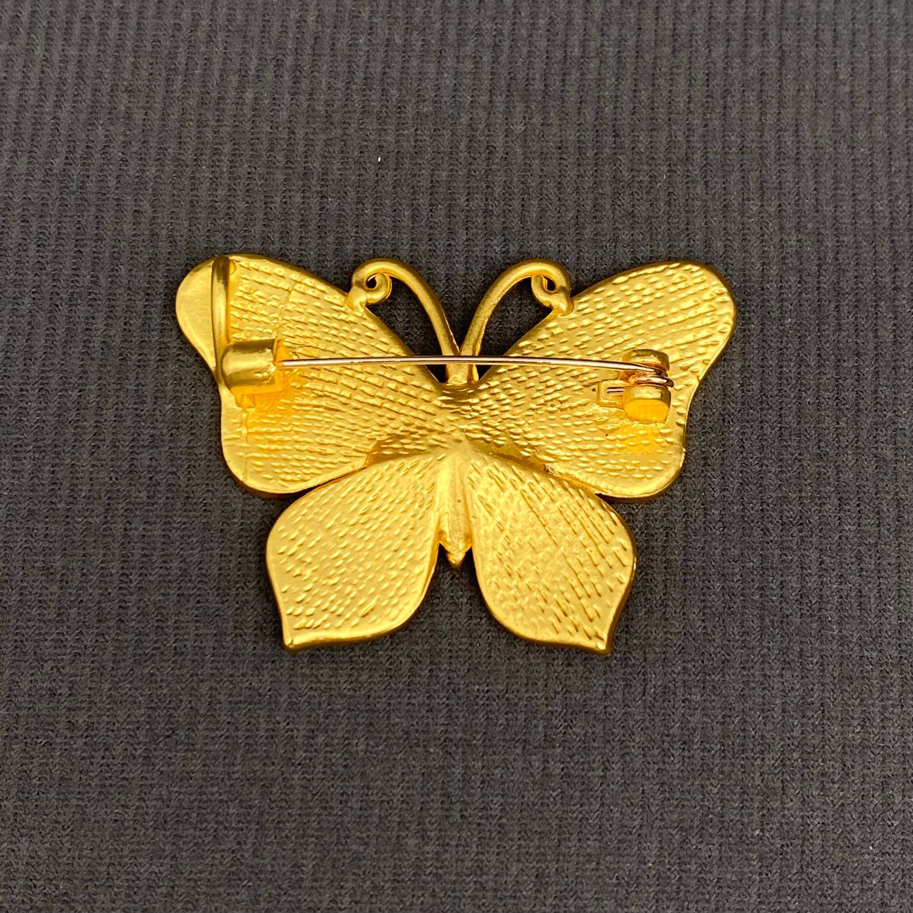 Back view of butterfly-shaped brooch with blue and gold design, showing the clasp mechanism