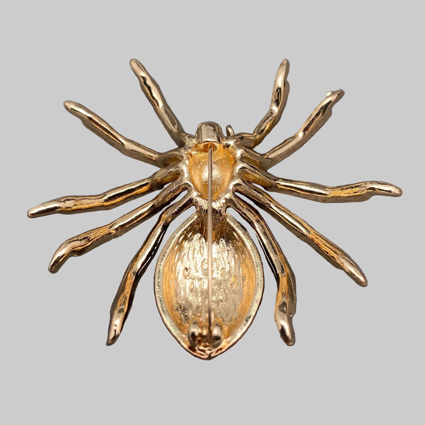 Back view of spider-shaped brooch with gold, red, and black details, showing the clasp mechanism