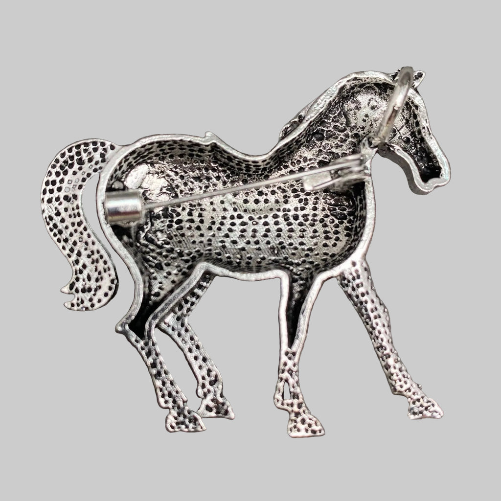 Back view of red horse-shaped brooch with blue saddle, showing the clasp mechanism