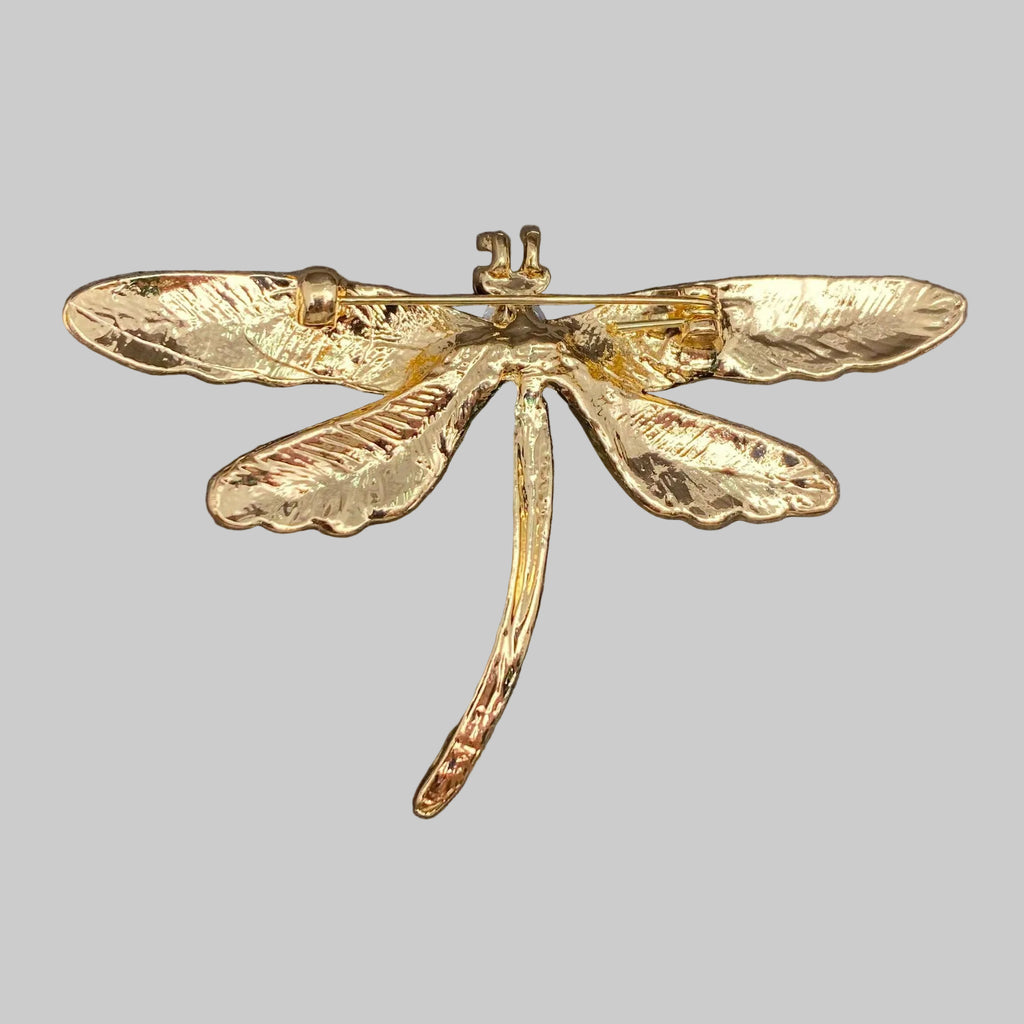 Back view of colorful dragonfly-shaped brooch showing the clasp mechanism, on a gray background