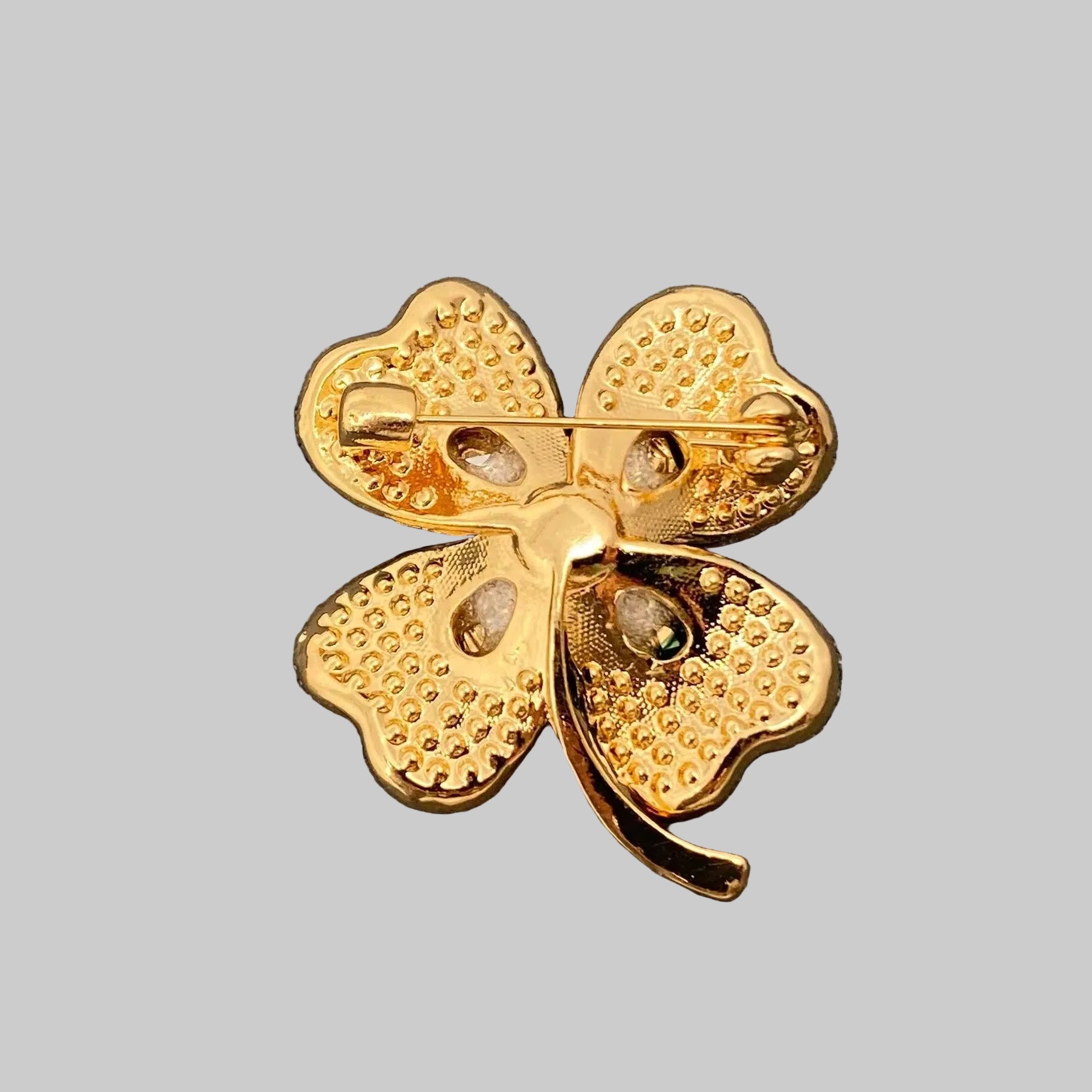 Back view of green four-leaf clover brooch with gold accents, showing the clasp mechanism