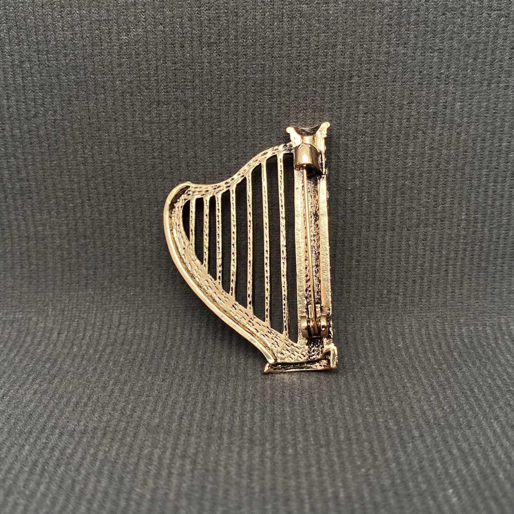 Back view of harp-shaped brooch with rhinestones, showing the clasp mechanism