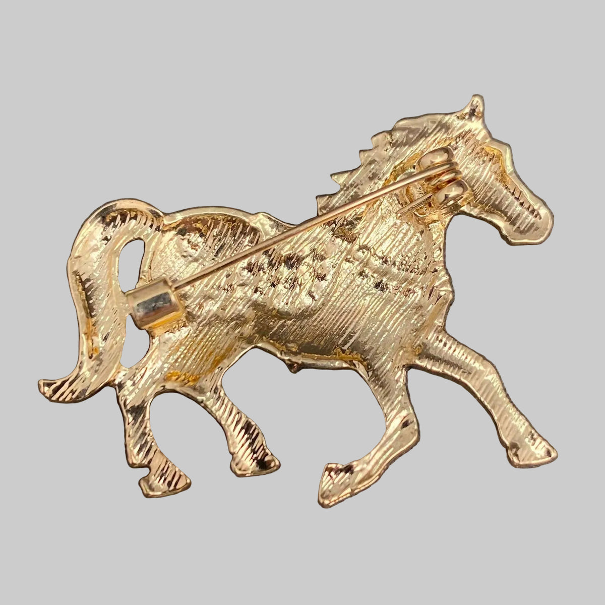 Back view of horse brooch, showing the clasp mechanism, against a gray background.