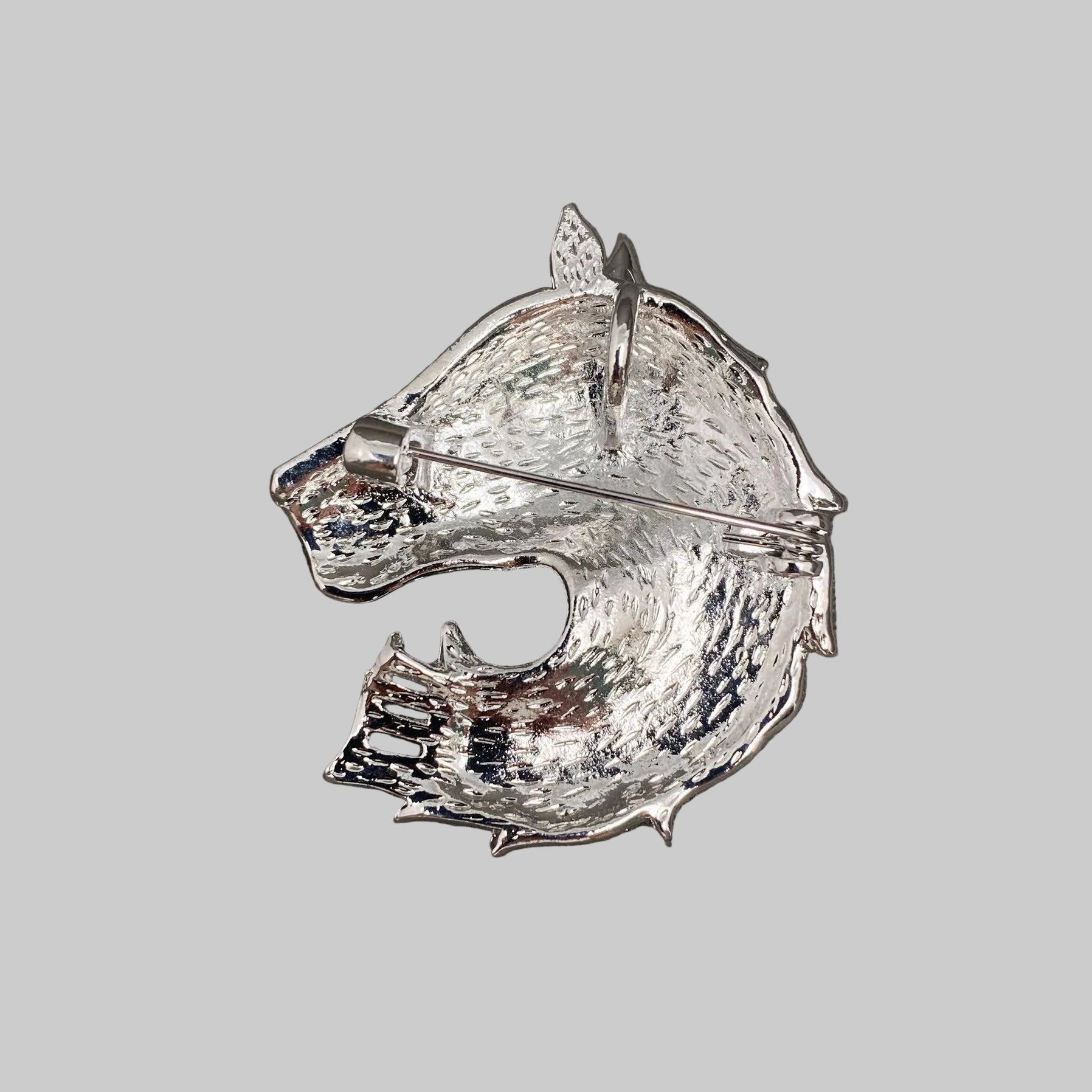 Back view of silver horse head brooch with gemstones, showing the clasp mechanism