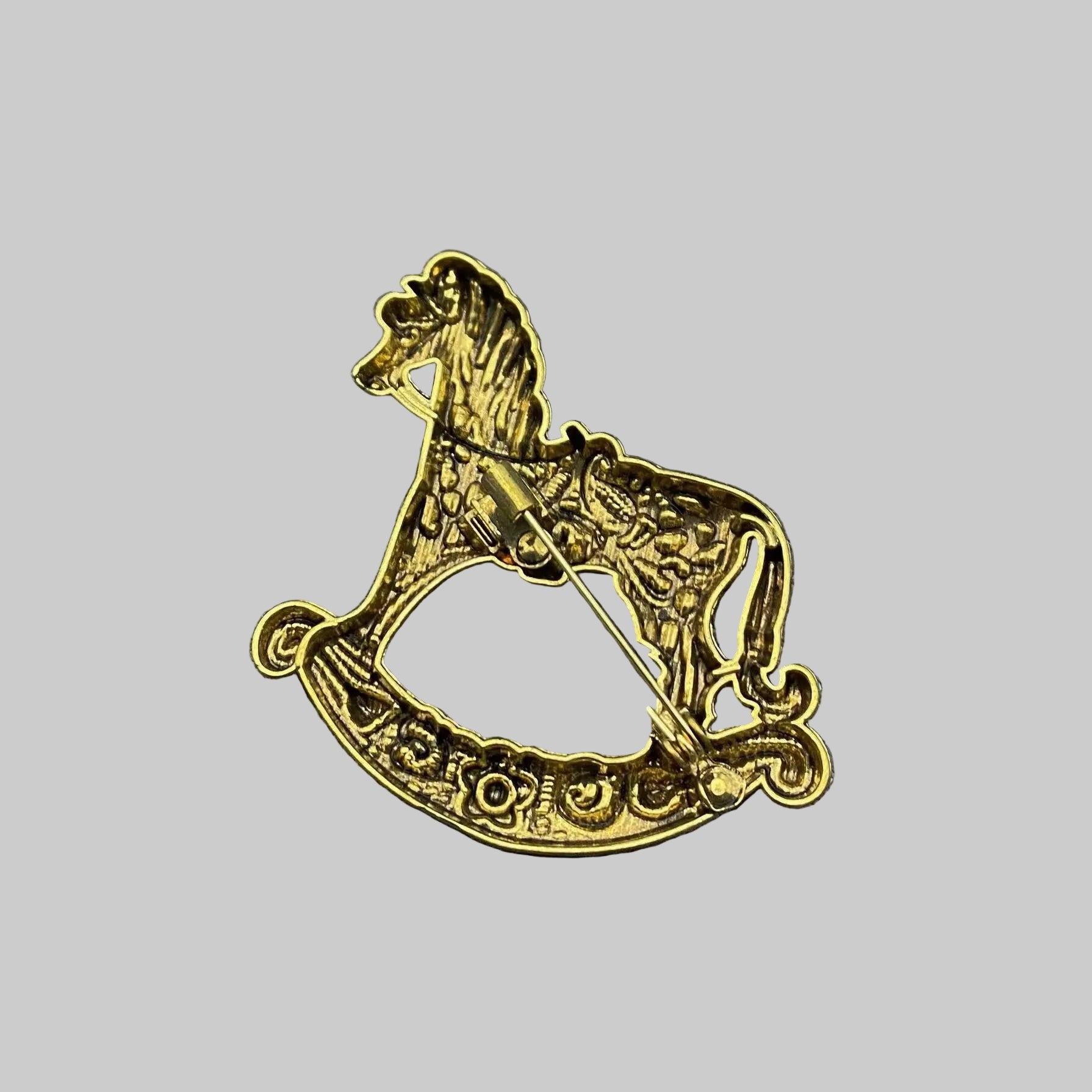 Back view of gold rocking horse brooch with floral details, showing the clasp mechanism