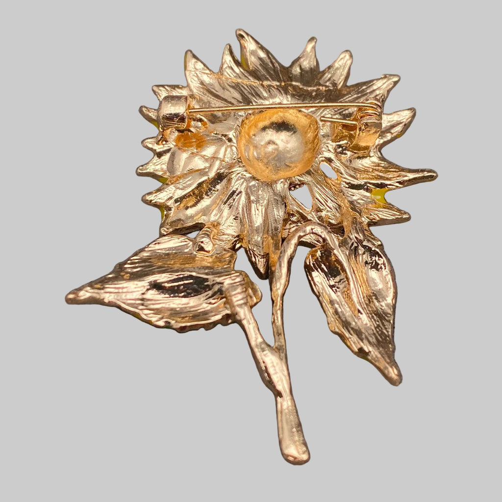 Back view of sunflower-shaped brooch, showing the clasp mechanism on a gray background