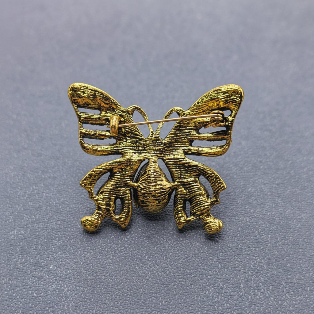 Back view of a butterfly-shaped brooch with gemstones, showing the clasp mechanism