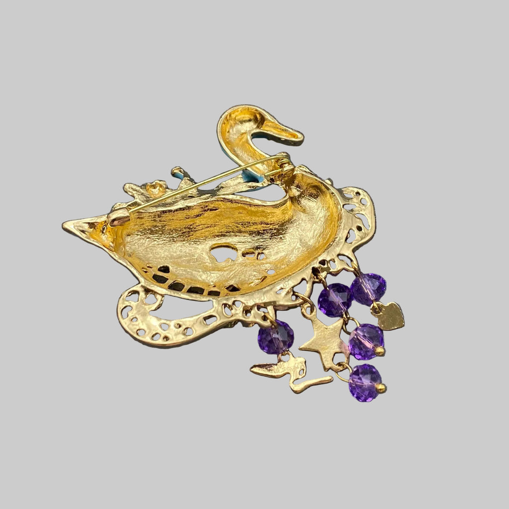 Back view of decorative brooch shaped like a swan with gold and purple accents, showing the clasp mechanism