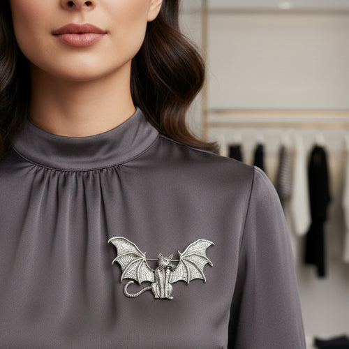 Silver metal bat-shaped brooch featuring a cat adorned with dimensional bat wings