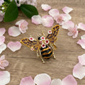 Decorative bee brooch with floral details on a wooden background