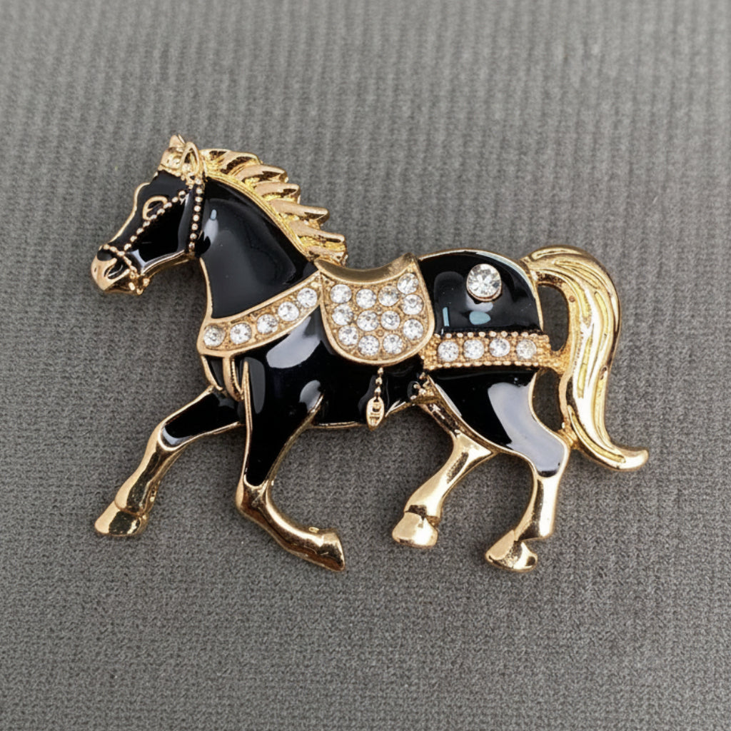 Black and gold horse-shaped brooch with rhinestones on a gray background