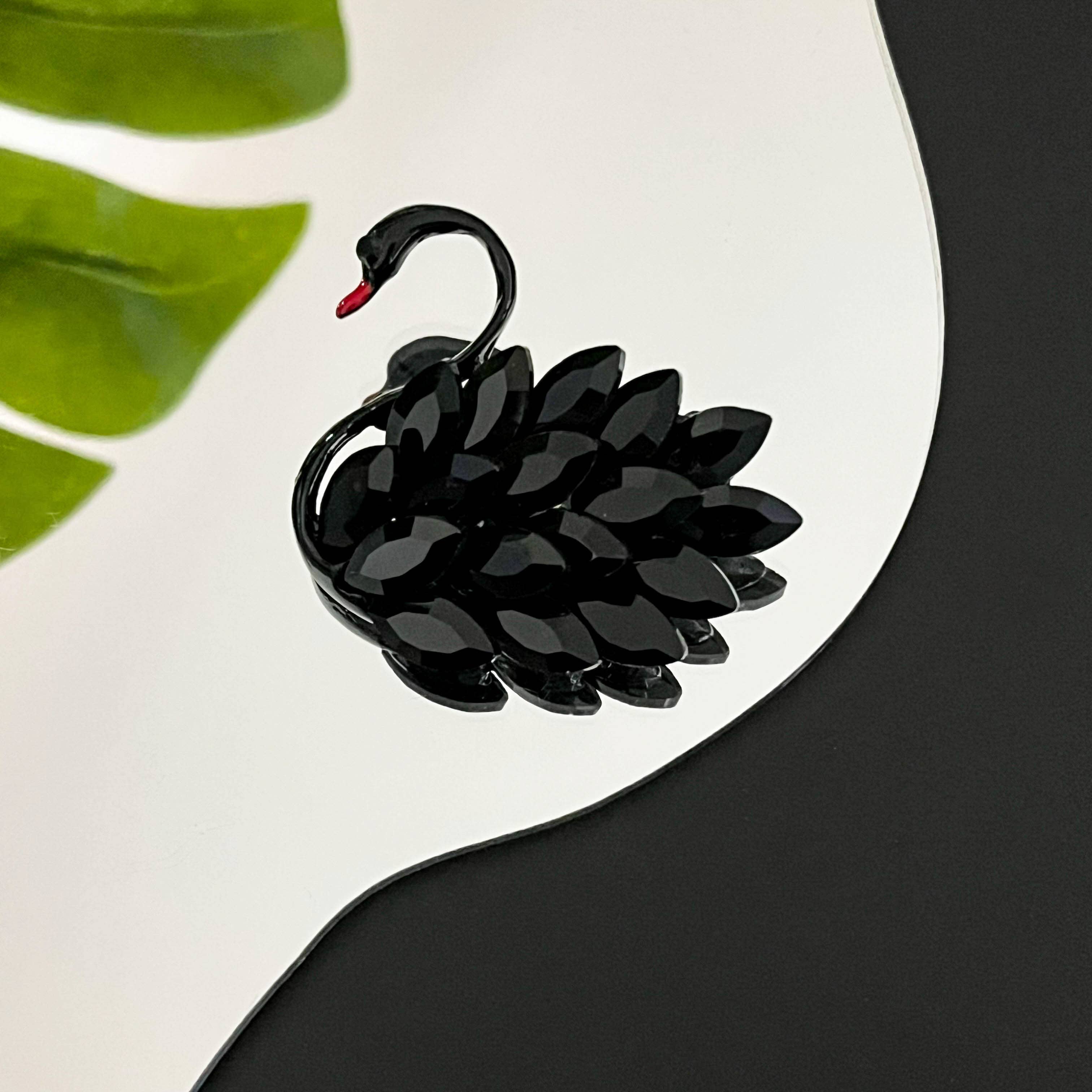 Black swan-shaped brooch on a white and black background