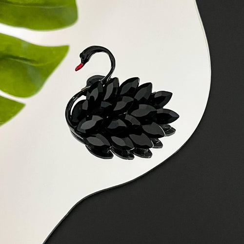 Black swan-shaped brooch on a white and black background