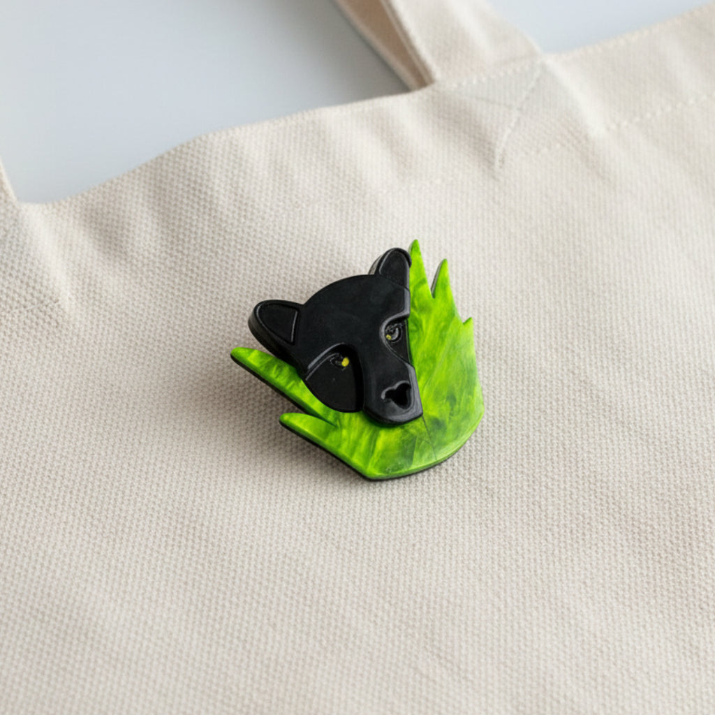 Black panther head on a green leaf brooch pinned on a tote bag