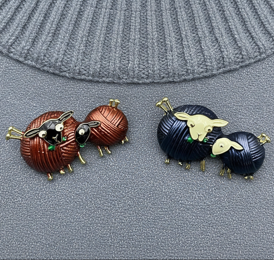 Pair of sheep-shaped brooch pins one set in brown and one set in black, on a gray background