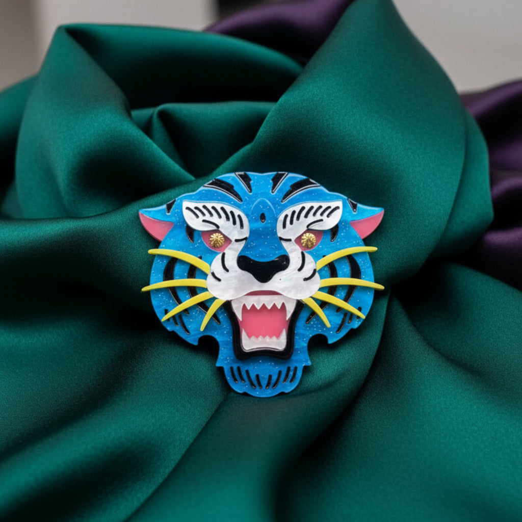 Colorful acrylic tiger head brooch on a green satin background