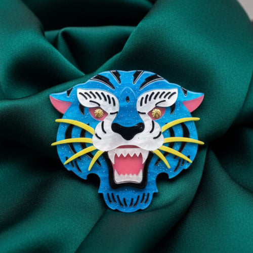 Colorful acrylic tiger head brooch on a green satin background