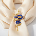 Gold and blue snake-shaped brooch pin on a ivory silk scarf