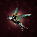 A colorful enamel bird brooch shaped like a flying swallow, featuring blue, green, and brown, with gold-tone metal accents, on a red background