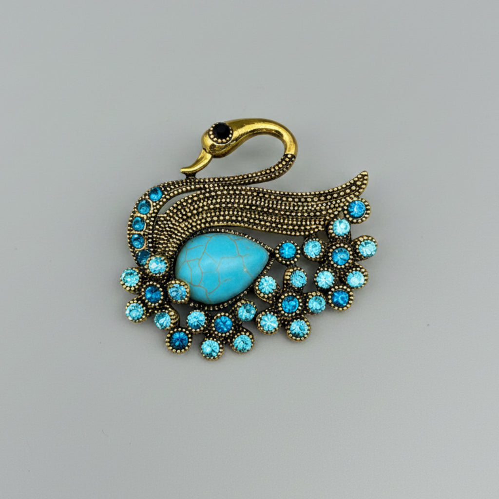 Blue rhinestone swan brooch on a gray background