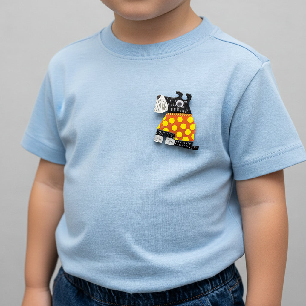 Dog-shaped brooch with black, orange, and yellow design pinned on a boy's t-shirt