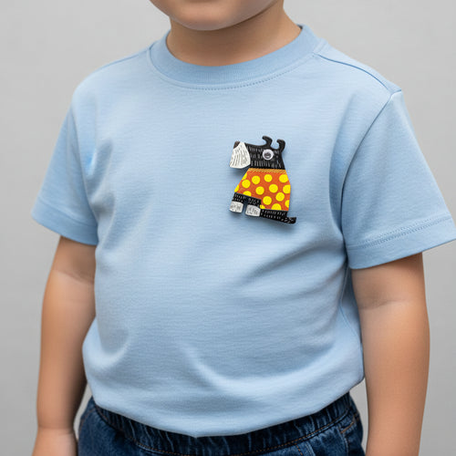 Dog-shaped brooch with black, orange, and yellow design pinned on a boy's t-shirt